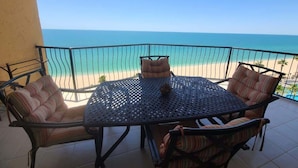 Un balcón con mesa y sillas, con vista a una playa.