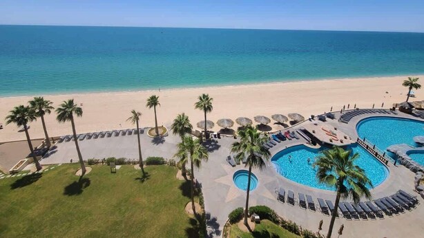 Un resort con piscina, palmeras y playa.