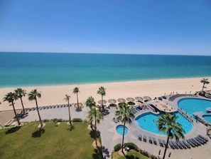 Un resort con piscina, palme e spiaggia.