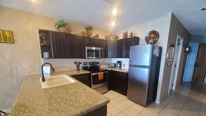 Una cocina con encimeras de granito, electrodomésticos de acero inoxidable y muebles oscuros.
