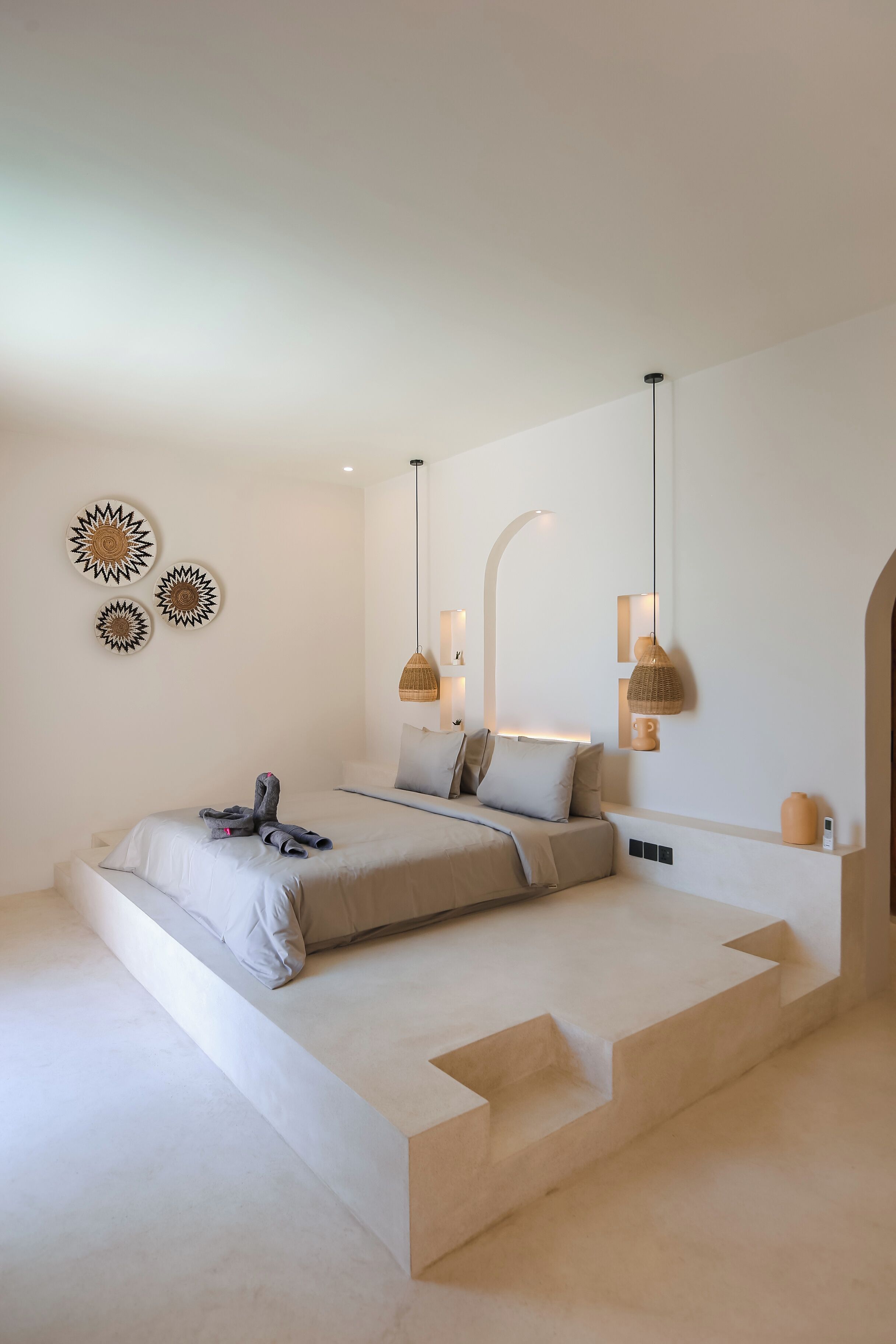 A modern bedroom with a low platform bed, wall-mounted sconces, and decorative wall art.