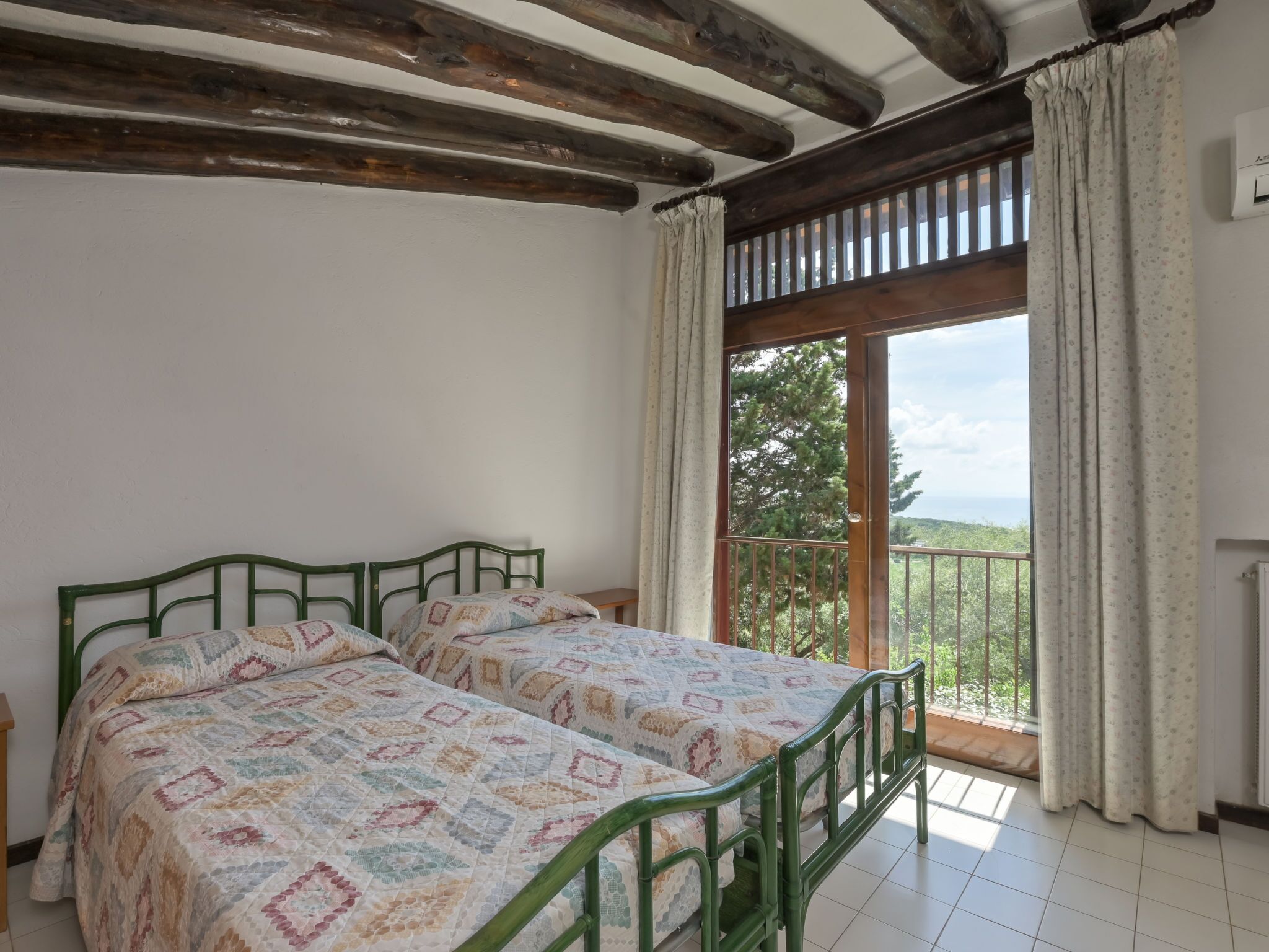 Une chambre avec un grand lit, une fenêtre donnant sur un beau paysage et un balcon.