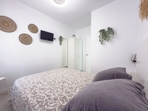 A bedroom with a bed, a TV, a mirror, and decorative wall art. - Villa Tarifa (Torrox)