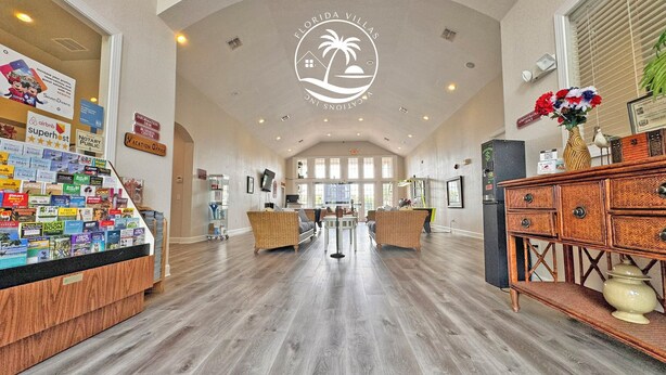 A spacious lobby with a high ceiling, a reception desk, and a wall displaying various travel brochures. - Seven Dwarfs Resort -Close to Disney (Kissimmee)