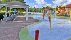 A children's play area with a water fountain, slides, and a covered seating area with lounge chairs. - Seven Dwarfs Resort -Close to Disney (Kissimmee)