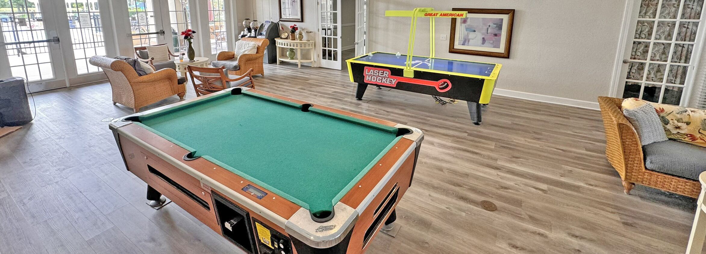 A pool table in a room with wicker furniture and a ping pong table.
