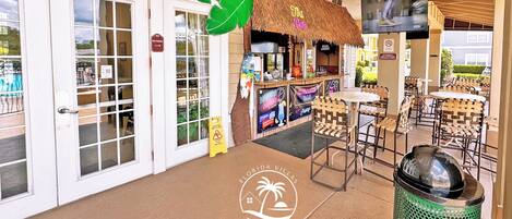A beachside bar with a thatched roof, outdoor seating, and a sign for 'Florida Villas'.
