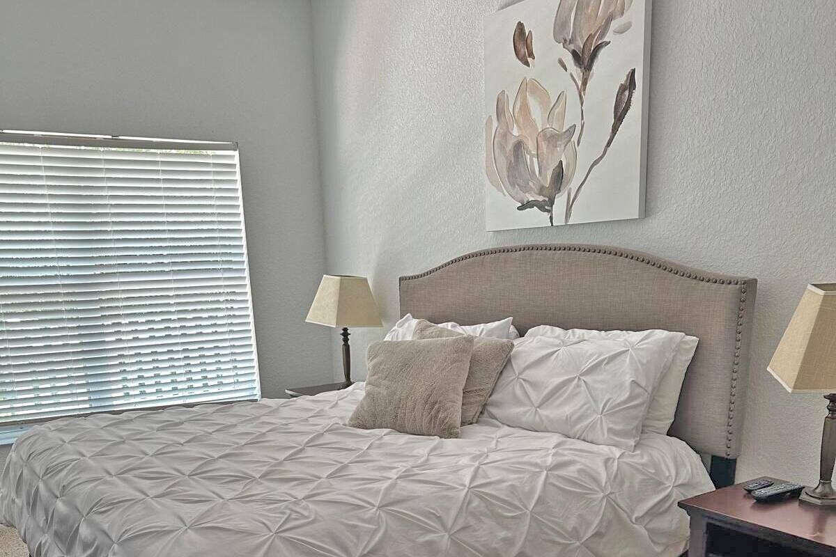 A bedroom with a bed, two bedside tables, a lamp on each table, and a painting on the wall.