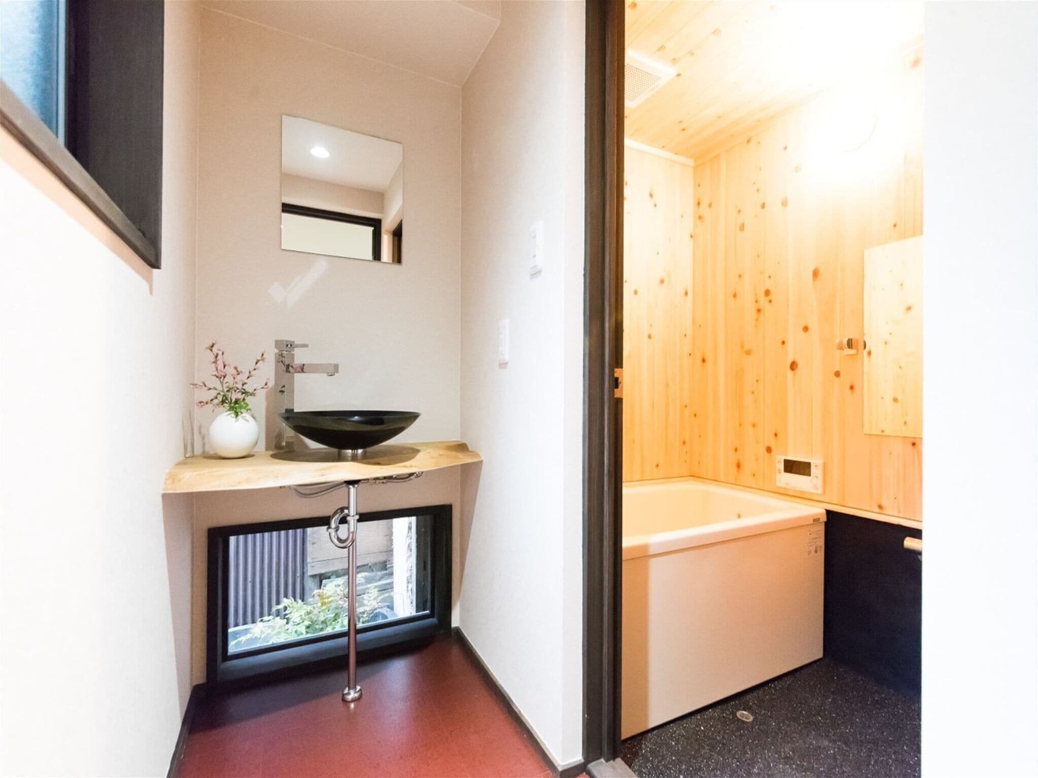 Une salle de bain moderne avec un intérieur en bois, un lavabo avec un receveur, un miroir et une fenêtre.