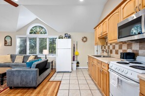 Une cuisine de taille réduite, équipée d’un réfrigérateur, d’une cuisinière et de meubles de rangement en bois.