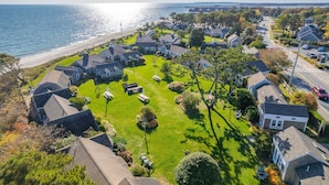 An aerial view of a coastal residential area with houses, lawns, and a beach.