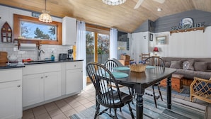 A kitchen with white cabinets, a dining table with chairs, a ceiling fan, and a sign that reads "SEASIDE".