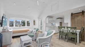 Amplia habitación con cama, sillas de mimbre, una mesa de comedor y zona de cocina.