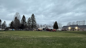 Un campo erboso con un edificio e alberi sullo sfondo.
