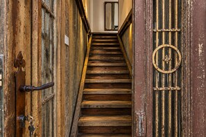 A wooden staircase leading to a room with a mirror and a door with a circular handle.