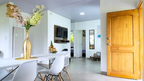 A modern kitchen with white cabinets, a wooden door, and a dining area with a white table and chairs. - Chalet - private family estate near Parque del Café - Coffee Region. (Quimbaya)