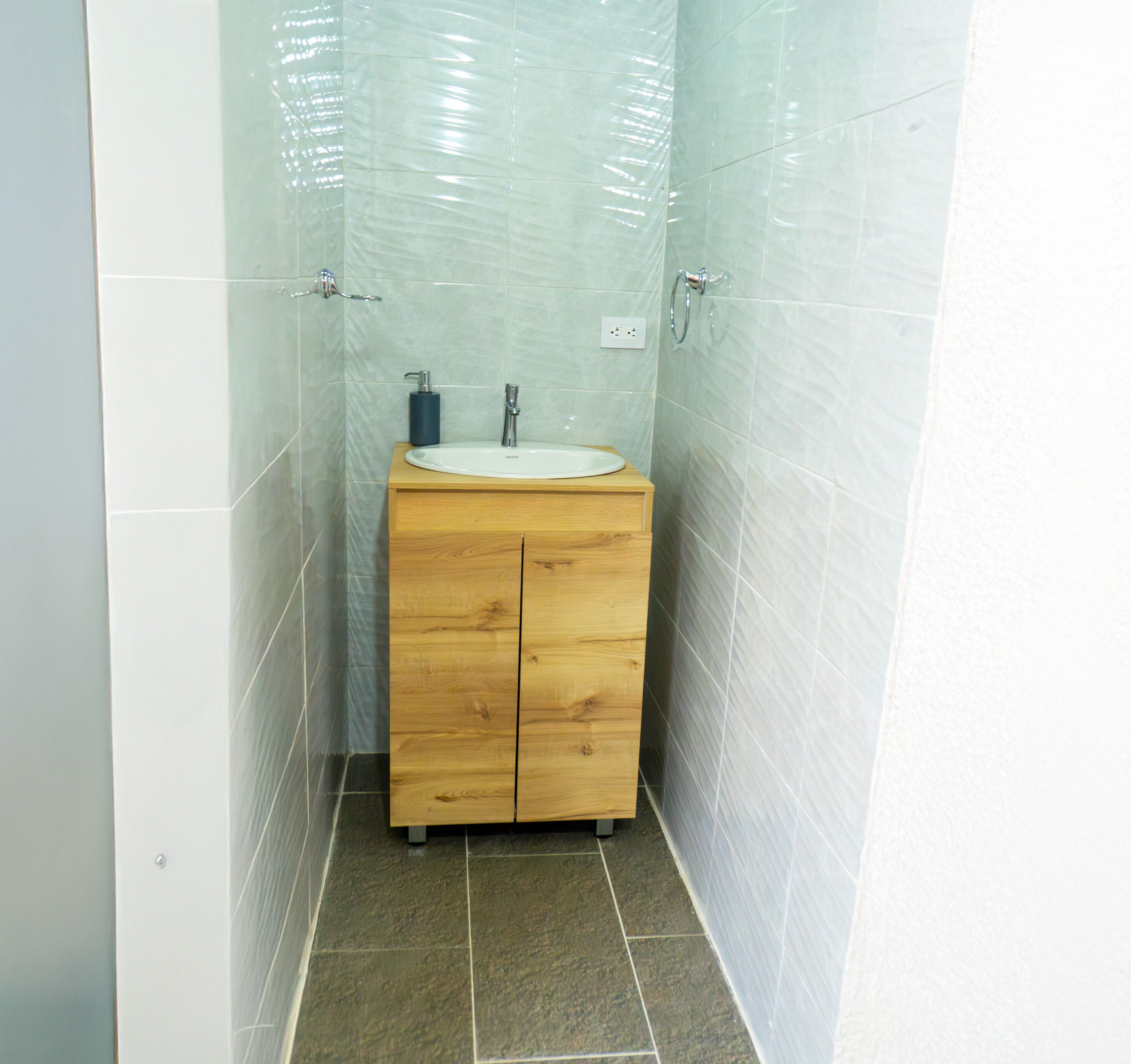Un bany amb un lavabo de fusta, un rentapeus blanc i un mirall.