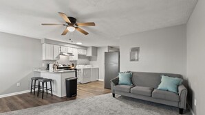 Une cuisine moderne avec des meubles blancs, un îlot central et un ventilateur de plafond.