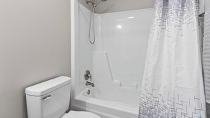 Une salle de bain moderne avec une douche à parois de verre, des toilettes blanches et un rideau de douche à motifs.