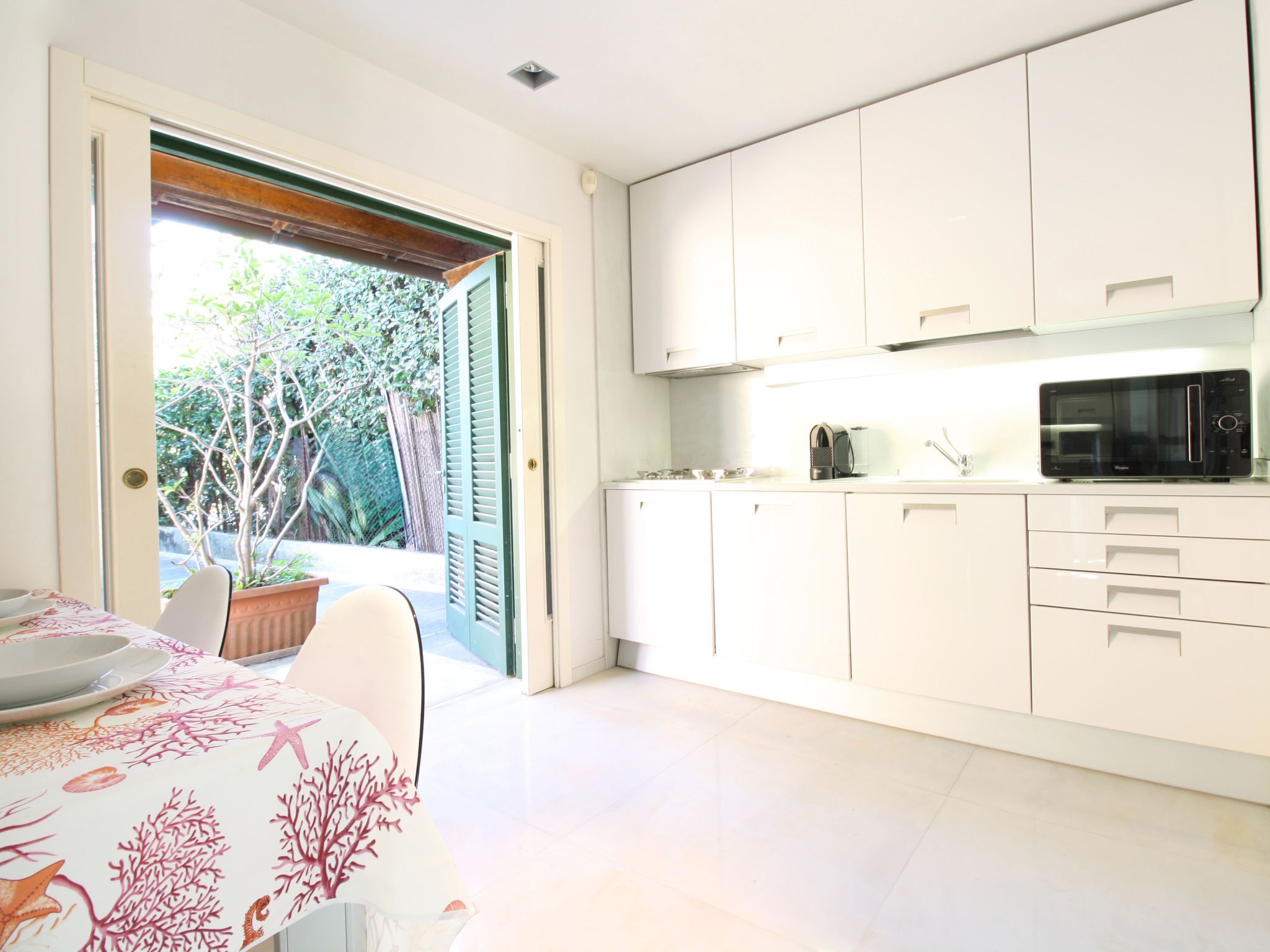 Una cocina moderna con armarios blancos, un microondas y una zona de comedor con mesa y sillas.