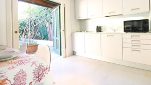 Una cocina moderna con armarios blancos, un microondas y una zona de comedor con mesa y sillas.