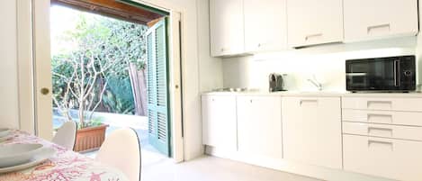 Una cocina moderna con armarios blancos, un microondas y una zona de comedor con mesa y sillas.