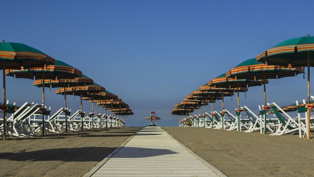 Un paseo marítimo con filas de sillas y sombrillas de playa.