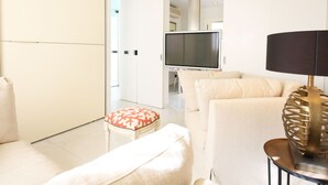 Una sala de estar moderna con un sofá, un reposapiés y un televisor.