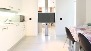 Una cocina moderna con armarios blancos, un microondas y un televisor de pantalla plana montado en la pared.