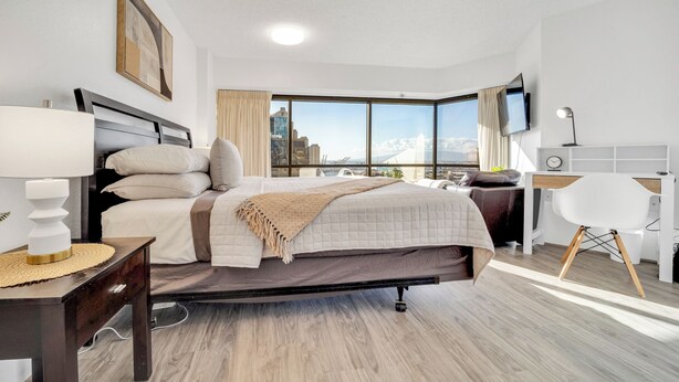 Een moderne hotelkamer met een groot bed, een bureau en een televisie.