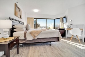 Moderni hotellihuone, jossa on suuri sänky, työpöytä ja televisio.