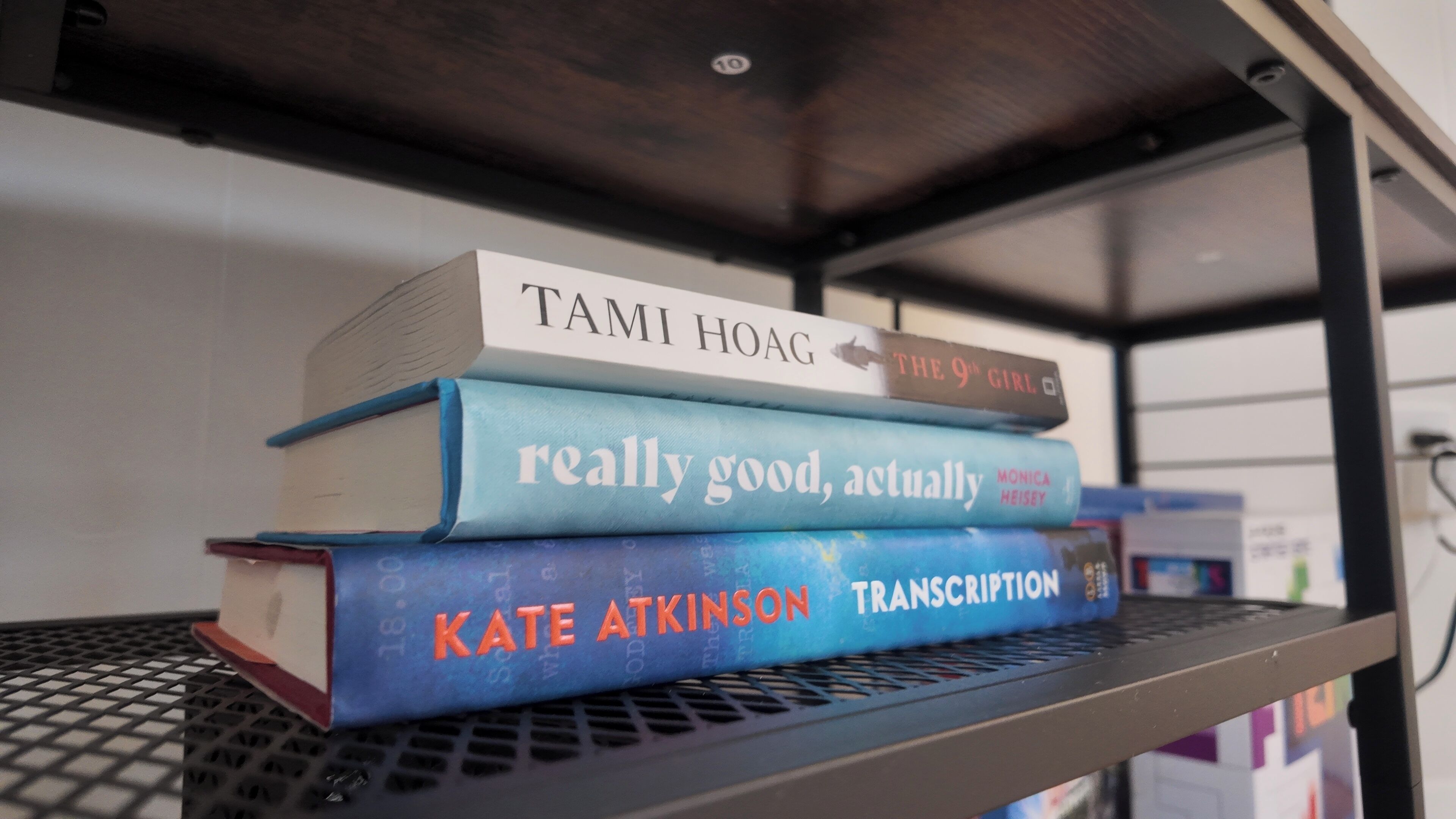 A metal shelf with three books stacked on it.
