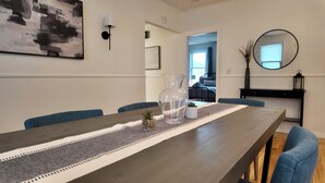 A dining area with a long table, blue chairs, a clear glass pitcher, and a small potted plant. - Newly Refreshed 3bd Spacious Unit Minutes from 290 (Worcester)