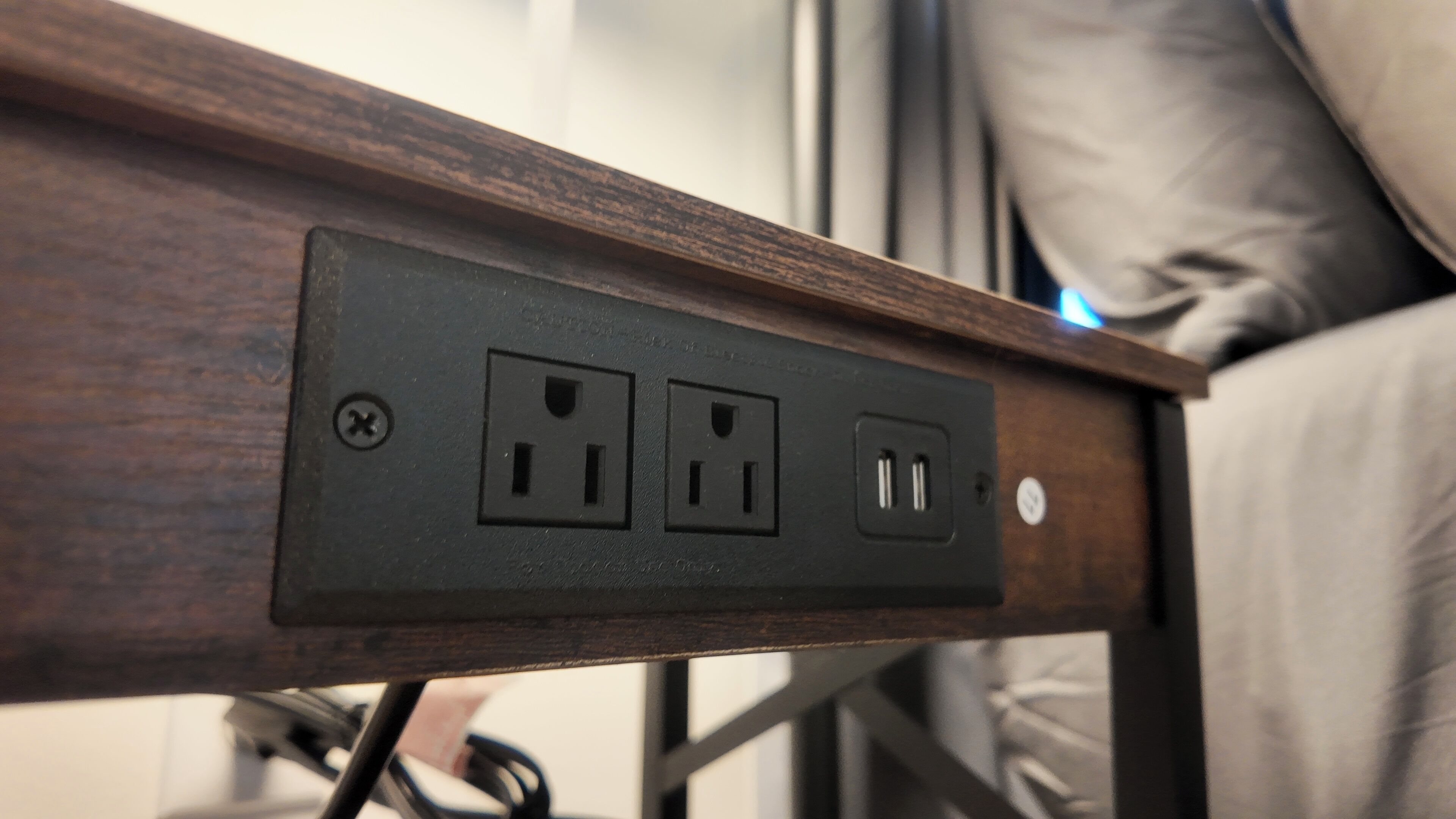Una mesita de noche de madera con un enchufe y puertos USB.