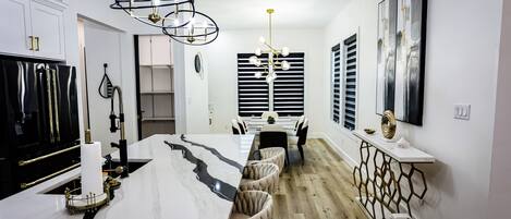 Una cocina moderna con encimera de mármol, horno empotrado y comedor con suelo de madera.