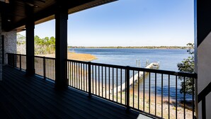 A covered deck with a view of a lake and a dock. - Charming waterfront 3-bedroom, 3 bath house with gourmet kitchen in Milton, FL (Milton)