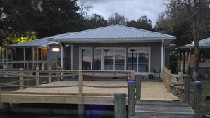 A wooden dock leading to a building with a metal roof, surrounded by trees. - 3-bedroom house in welcoming Moss Point with AC, WiFi (Moss Point)
