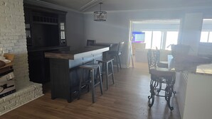 A kitchen with a bar area, wooden flooring, and a white brick wall. - 3-bedroom house in welcoming Moss Point with AC, WiFi (Moss Point)