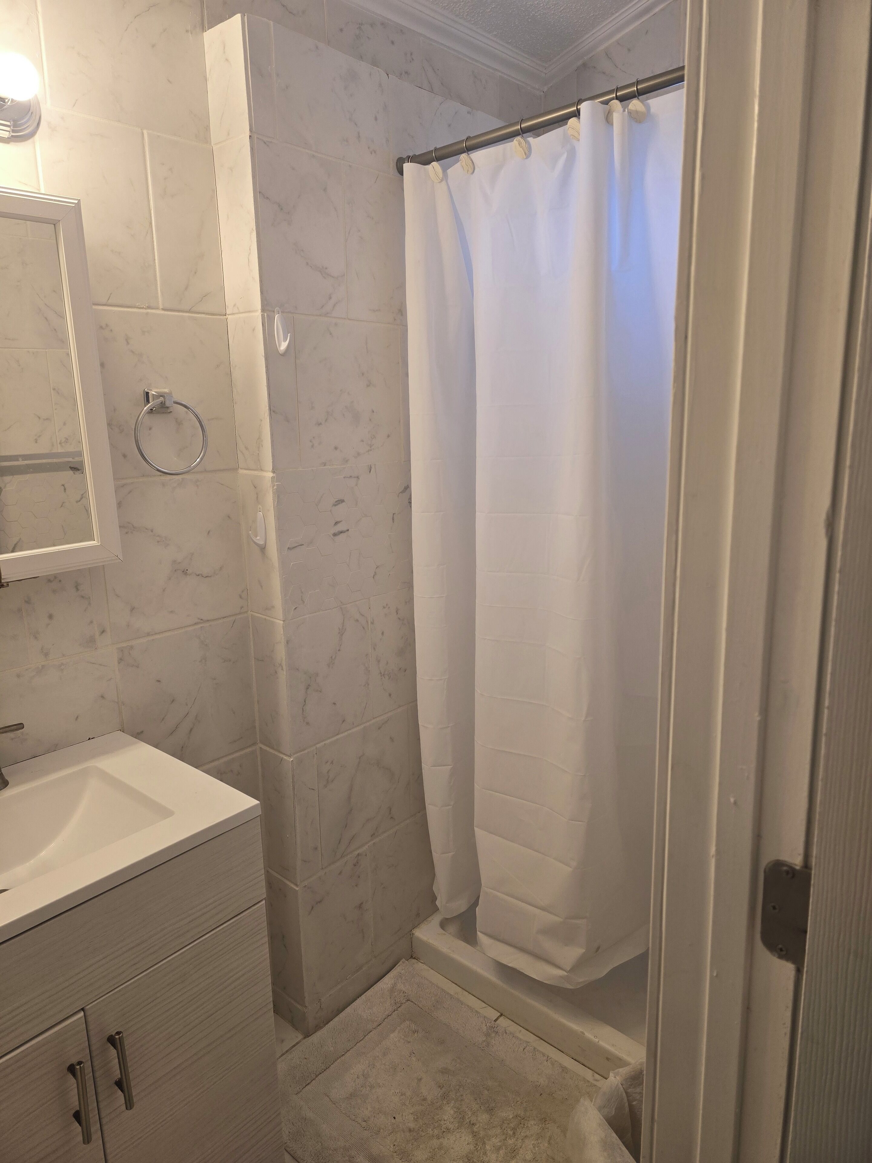Un baño con un lavabo blanco, un espejo, un tocaderecados y una cortina de ducha.