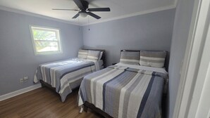 A bedroom with two beds, a ceiling fan, a window, and a door. - 3-bedroom house in welcoming Moss Point with AC, WiFi (Moss Point)