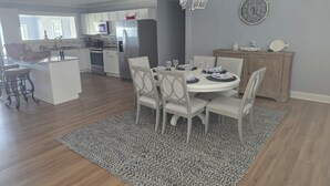 A modern kitchen with white cabinets, stainless steel appliances, and a dining area with a round table and white chairs. - 3-bedroom house in welcoming Moss Point with AC, WiFi (Moss Point)