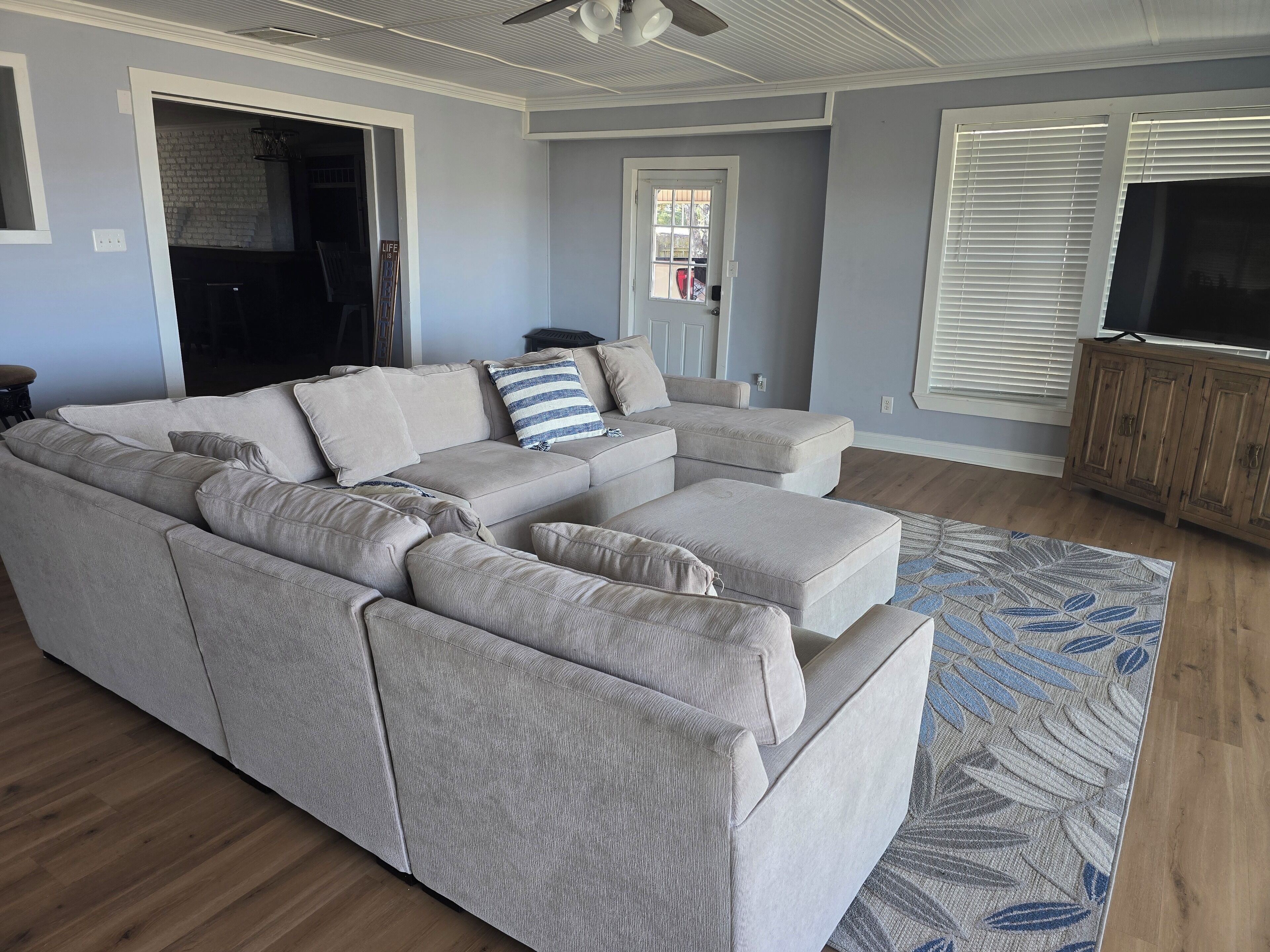 A living room with a sectional sofa, a patterned rug, and a wooden cabinet.