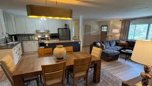 A modern kitchen with white cabinets, a built-in oven, and a large island with a round table. - Charming 4-bedroom retreat, AC, sauna and hot tub close to Sequoia Nat'l Park (Three Rivers)