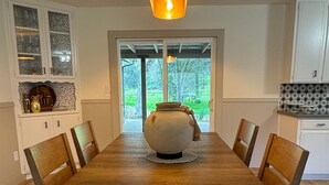 A dining area with a wooden table, chairs, a central decorative vase, and a modern pendant light. - Charming 4-bedroom retreat, AC, sauna and hot tub close to Sequoia Nat'l Park (Three Rivers)