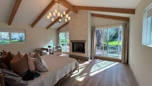A bedroom with a large bed, a fireplace, and a view of a garden. - Charming 4-bedroom retreat, AC, sauna and hot tub close to Sequoia Nat'l Park (Three Rivers)