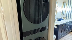 A compact, modern laundry room with a built-in washer and dryer, a vanity with a mirror, and a wooden floor. - Charming 4-bedroom retreat, AC, sauna and hot tub close to Sequoia Nat'l Park (Three Rivers)