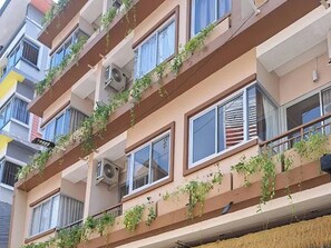A multi-story building with balconies, air conditioning units, and some greenery. - The Rock Patong Comfort Stay (Patong)