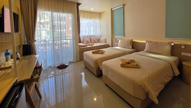 Una habitación de hotel con dos camas, un escritorio, un televisor y una ventana con cortinas.