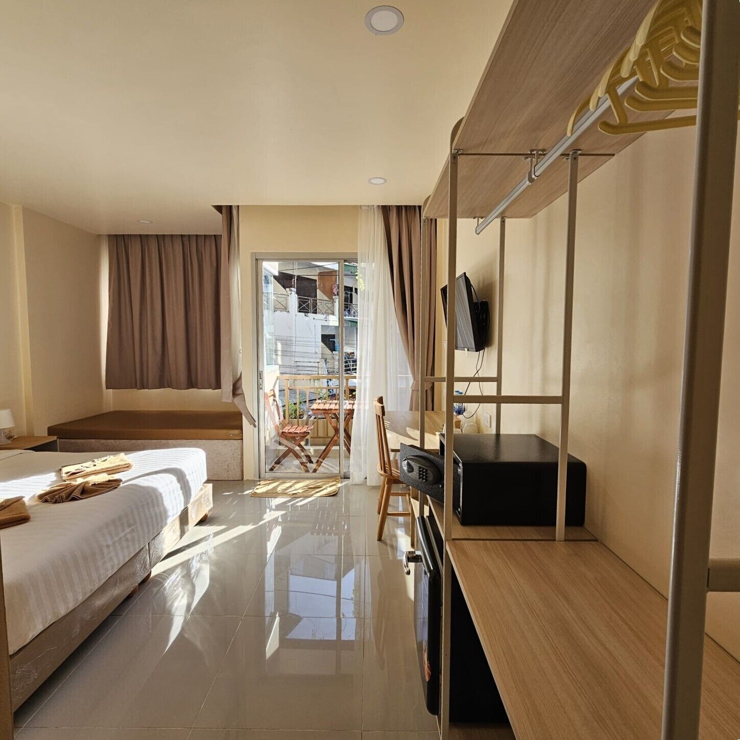 A hotel room with a bed, a desk with a chair, a television, and a balcony with a view.