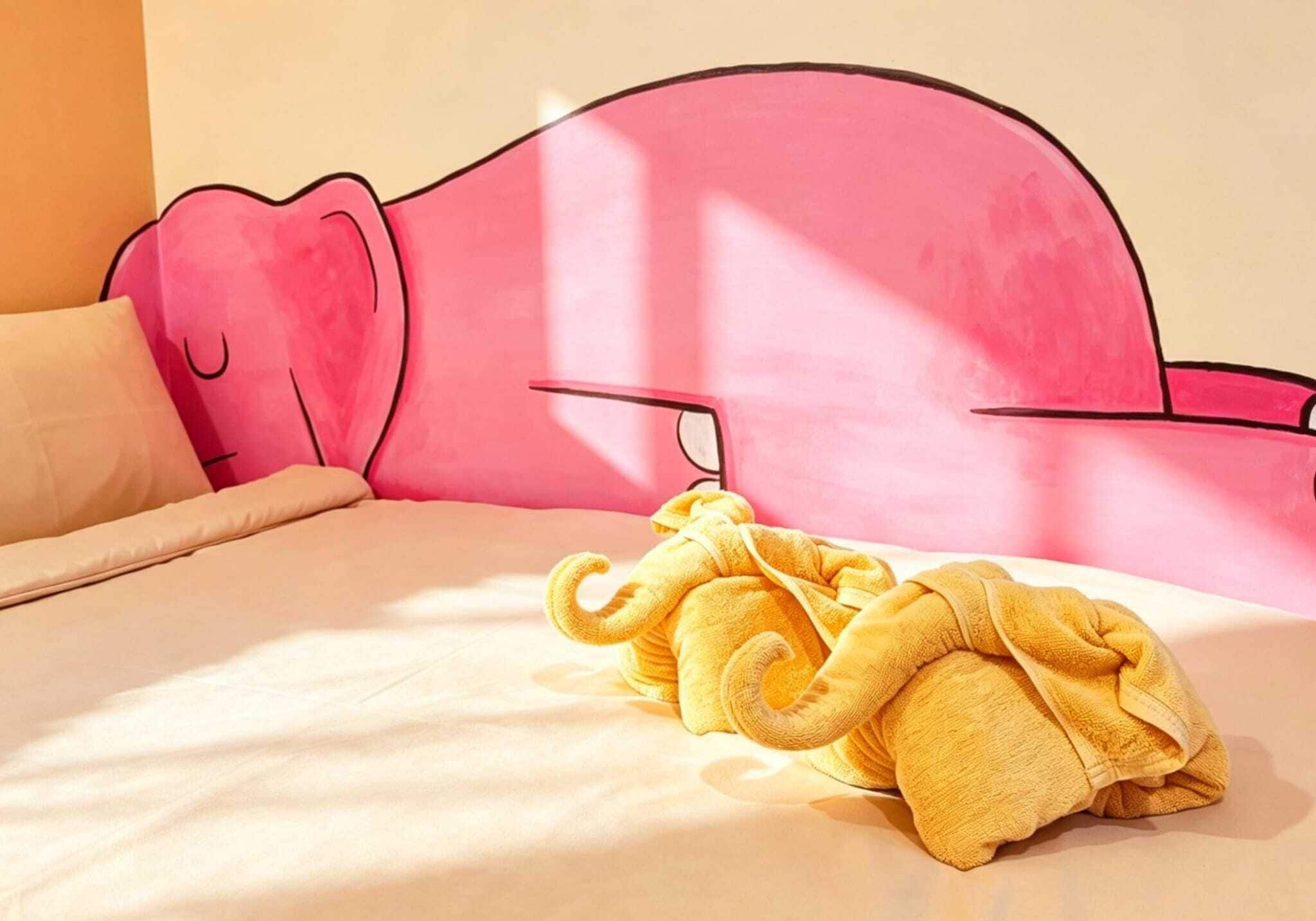 Een bed met een roze hoofdbord, een gele handdoek en een beige kussen.